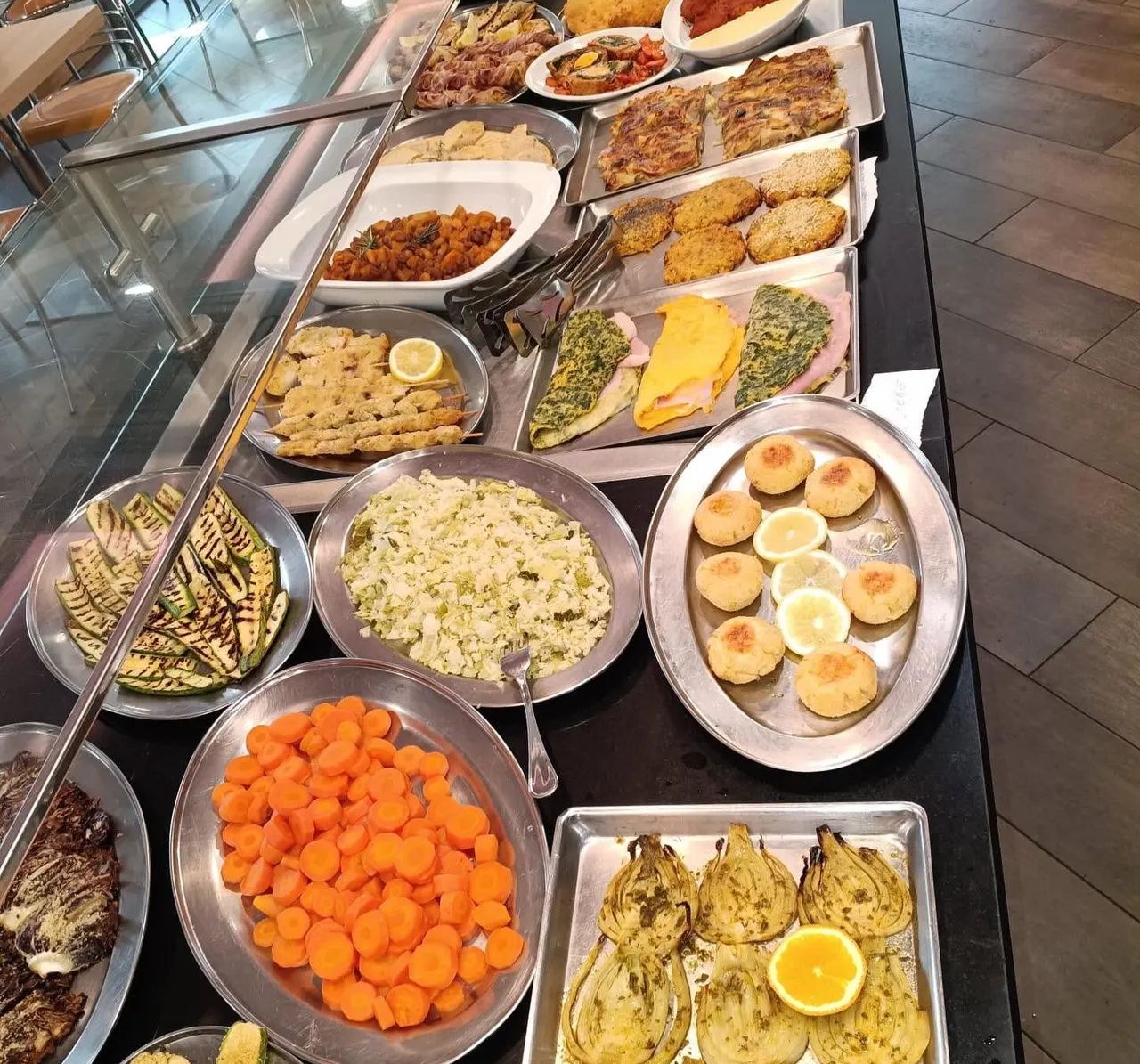 Il banco dei piatti pronti: verdure grigliate, polpette al limone, frittate e finocchi al forno in fila sul bancone