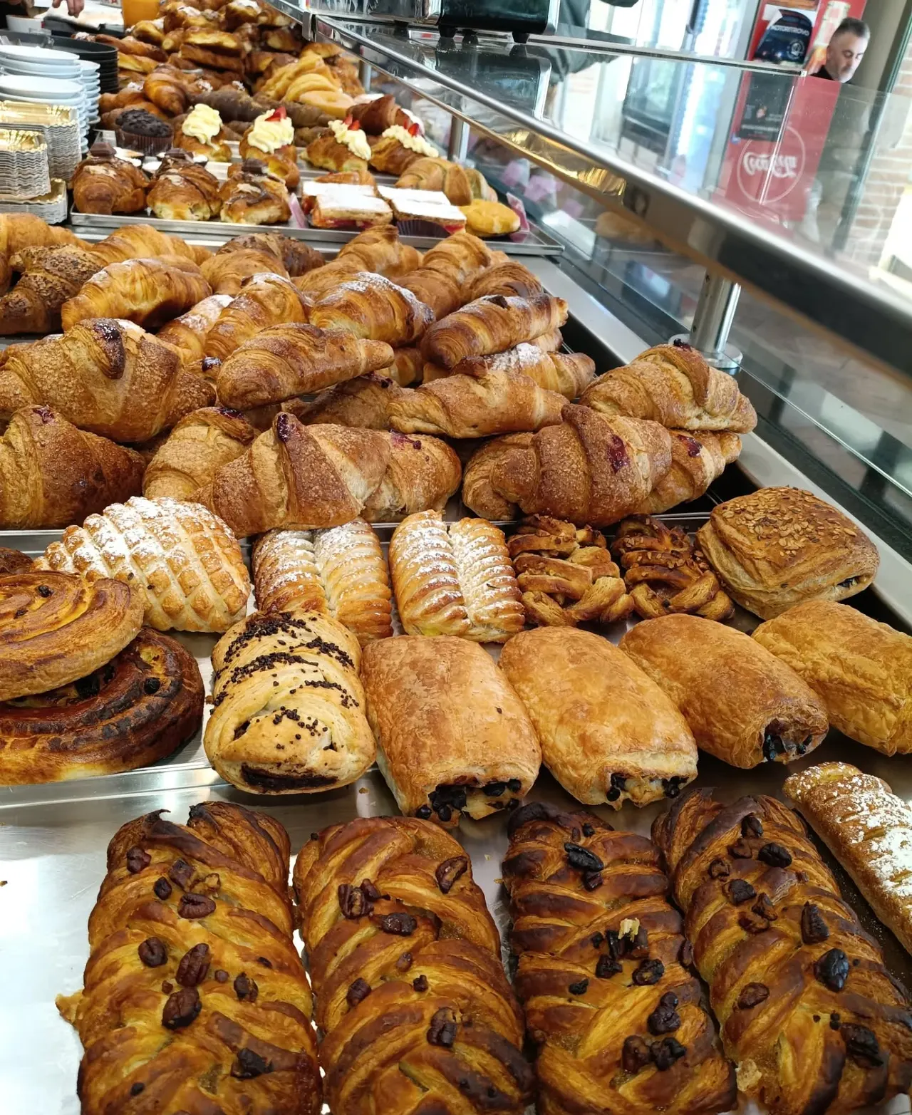 Il banco della colazione: croissant, sfoglie e trecce appena sfornate, in fila sotto la vetrina