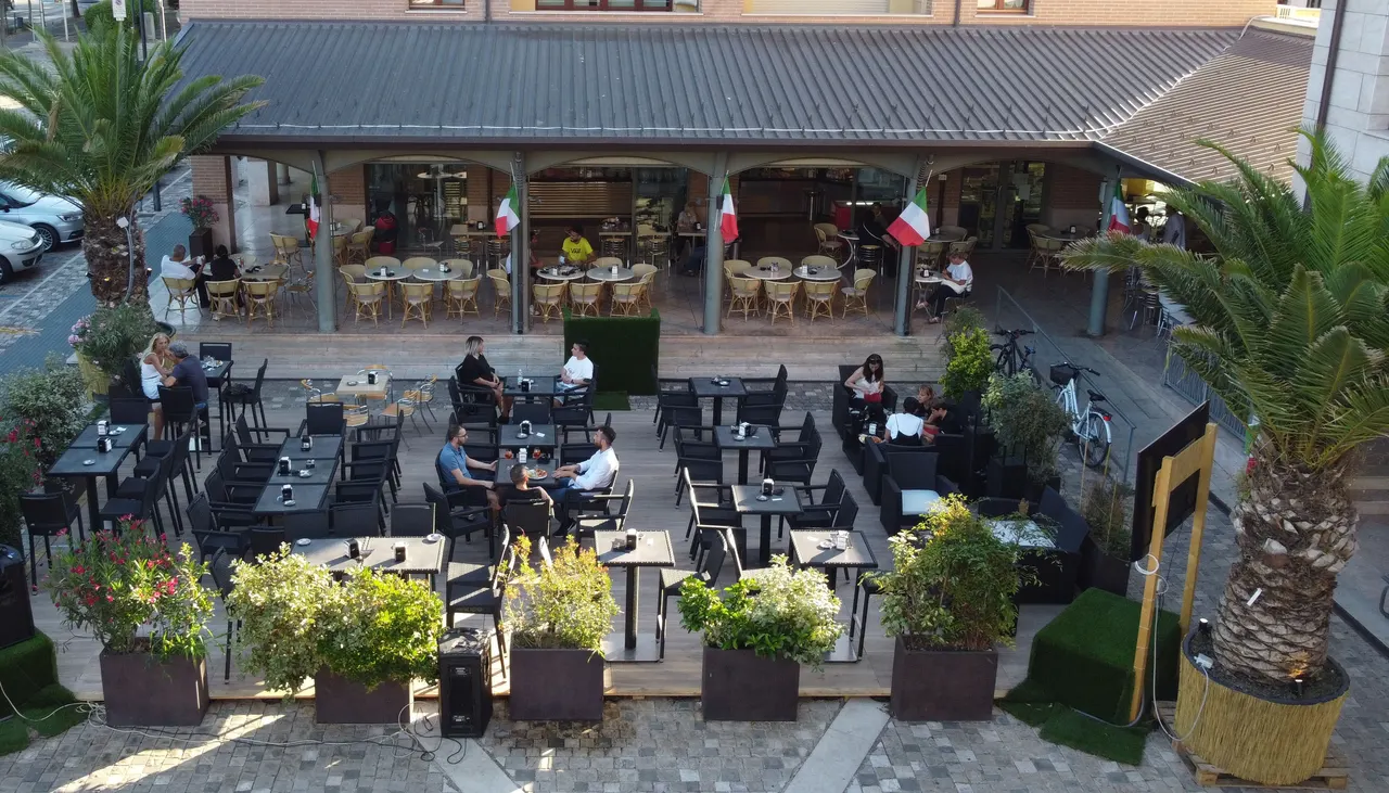 Il Caffè Gabrè visto dall'alto: il dehors tra le palme di Piazza del Vecchio Ghetto, i tavolini pieni sotto il portico